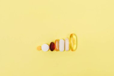 Sarı arka planda çeşitli tıbbi tabletlerin ve hapların koleksiyonu, boşluğu kopyala