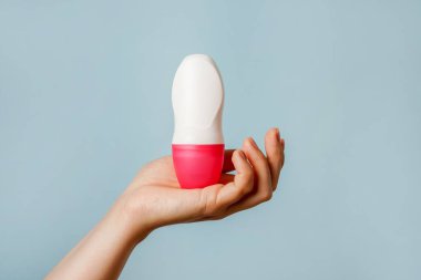 Kadın eli mavi arkaplanda vücut deodorantı tutuyor, boşluğu kopyala
