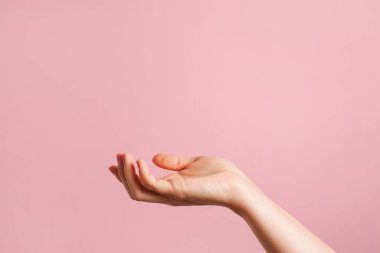 Elini aç ve yardım etmeye ya da almaya hazır ol. Kozmetik ürünler için bir podyum olarak el. kopyalama alanı olan pembe arkaplan