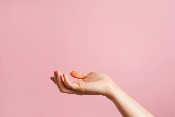 Hand open and ready to help or receive. hand as a podium for cosmetic products . pink background with copy space