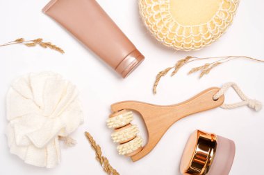 Doğal organik kozmetik ürünleri. Beyaz arka planda buğday dikenli cilt bakım ürünleri. Krem ve losyonlu kozmetik kaplar, masaj aleti, bez..