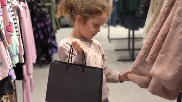 Cute Child Girl Black Paper Bag Chooses Fur Coat Shopping — Stock Video