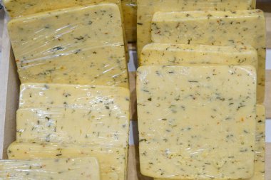 Sarı peynir ve bitkiler bir mağazanın rafında duruyor.