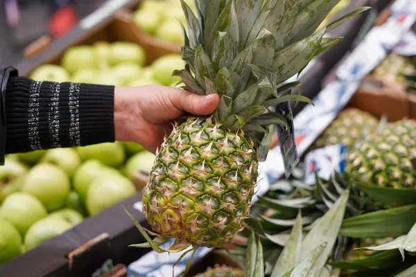 Pineapple in the female hand in the food store