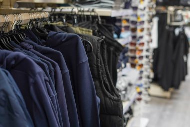 Alışveriş merkezindeki askılarda asılı erkek spor kıyafetleri, erkekler için giyim mağazası.