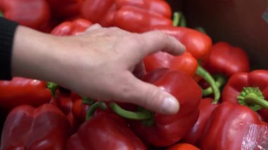 Kadın süpermarkette ya da haftalık markette kırmızı biber seçiyor.