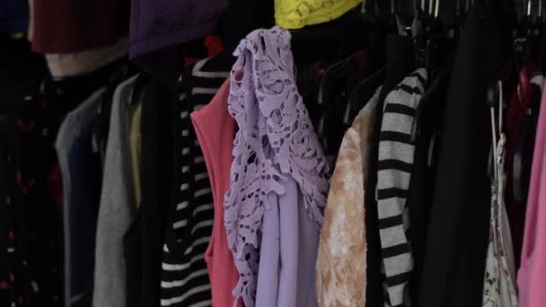 Женщина Покупает Подержанную Одежду Благотворительном Магазине Смотрит Лиловую Футболку — стоковое видео