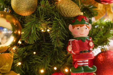 Noel ağacında altın ve kırmızı süslemeleri olan Noel Elfi