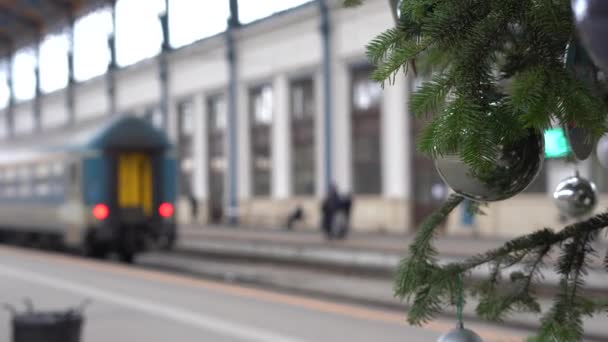 クリスマスツリーの枝を持つ鉄道駅の列車 冬の旅行の概念 — ストック動画