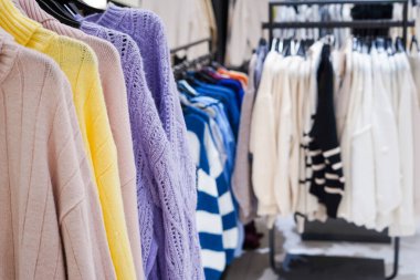 Colorful women's clothes on hangers in a retail shop. Fashion and shopping concept