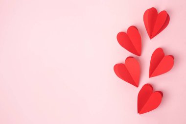 Pembe pastel arka plan üzerinde kağıt kırmızı kalpler, kopyalama alanı. Aziz Valentine, Anneler Günü, doğum günü tebrik kartları, davetiye, kutlama konsepti