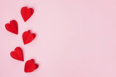 Pembe pastel arka plan üzerinde kağıt kırmızı kalpler, kopyalama alanı. Aziz Valentine, Anneler Günü, doğum günü tebrik kartları, davetiye, kutlama konsepti
