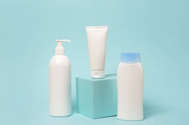 Mavi arkaplanda üç beyaz kozmetik ürün modeli