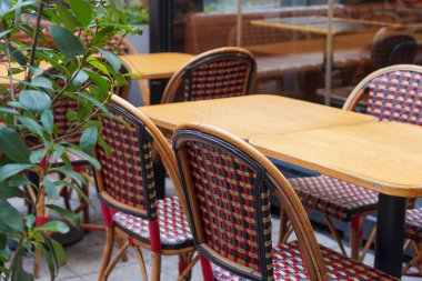Açık hava boş restoran terasında saksı bitkileri, masa ve sandalyeler.