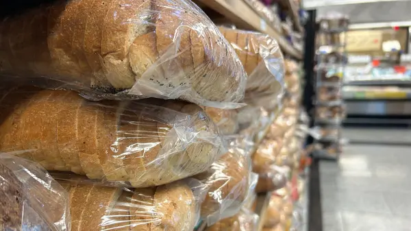 stock image A close-up view of packaged loaves of bread stacked on a shelf in a grocery store