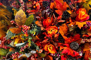 Renkli yapraklar, böğürtlenler, kozalaklar ve zengin portakal güllerinin karışımından oluşan sonbahar yaprakları verimli ve şenlikli bir görüntü oluşturur.