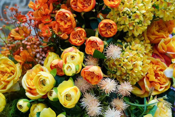 Turuncu ve sarı çiçeklerin çeşitli dokularla karışımı, canlı ve renkli bir çiçek sergiliyor.