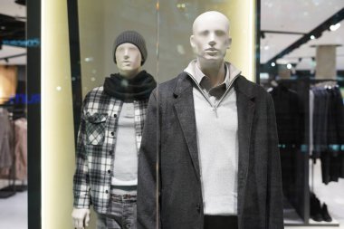 Bir mağazanın vitrininde kışın giyinmiş iki erkek manken.