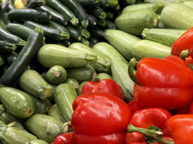 Taze yeşil kabaklar ve açık yeşil kabaklar, ön planda parlak kırmızı çan biberleri tarafından sunulan çarpıcı bir kontrastla