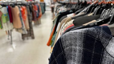 Giysilerle dolu rafları olan bir giyim mağazası.