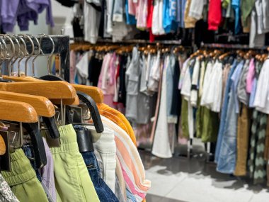 Pantolon, etek ve üst kısımları renkli giysilerle dolu bir giyim mağazası.