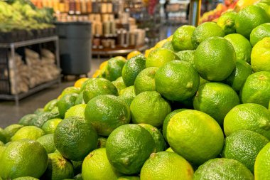 Taze, parlak yeşil limonlar bir marketin üretim bölümüne istiflenmiş.