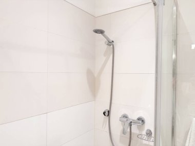 Modern bir banyo banyosu. Pürüzsüz krom bir duş başlığı var. Esnek bir hortuma bağlı.