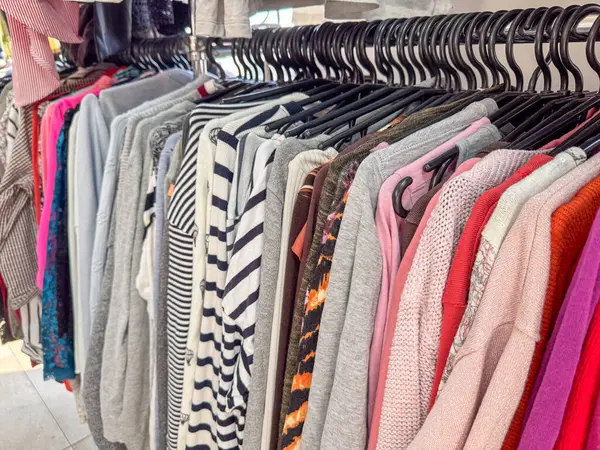 Bir elbise askısı çeşitli dokularda ve desenlerde süveter ve üstlerin renkli bir karışımını gösterir.