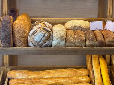 Fırındaki ahşap raflarda düzgünce sergilenen taze ekmek somunları.
