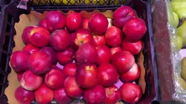 kırmızı nektarlar ve armutlar yapay ışıklandırma altında bir markette veya bakkalda sergilenir