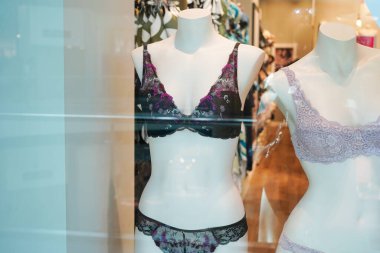 Mağaza vitrininde dantelli iç çamaşırı setleri giyen mankenler. Detaylı desenlere ve dokulara sahipler.