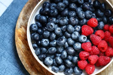 Bir kasede taze seçilmiş ahududu ve yabanmersini. Sağlıklı atıştırmalıklar. Tatlı olarak böğürtlen. Yakın plan..