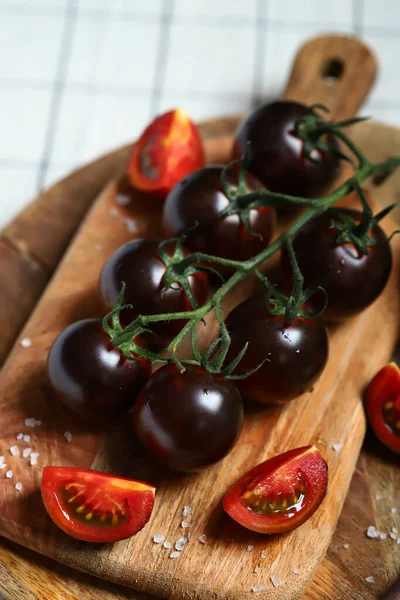 Black tomatoes with sea salt on a wooden board.