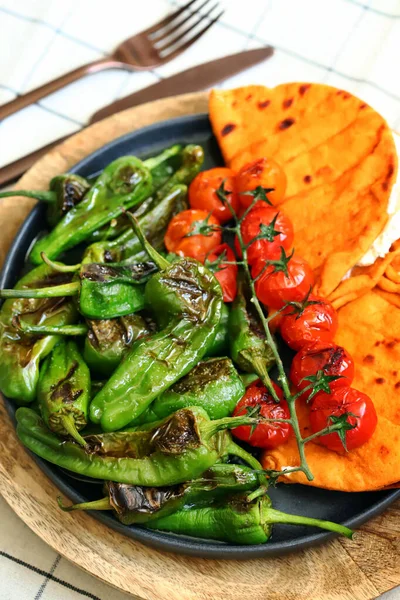 Grilled jalapeno peppers, cherry tomatoes and pita with cream cheese on a plate. Healthly food. Arabic style.