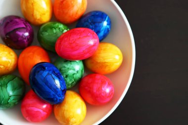 Siyah arka planda beyaz tabakta renkli yumurtalar..