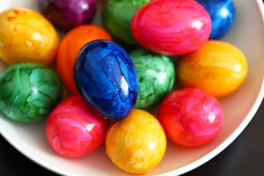 Siyah arka planda beyaz tabakta renkli yumurtalar..