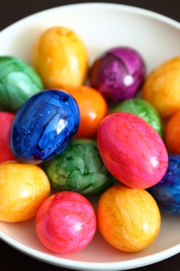 Siyah arka planda beyaz tabakta renkli yumurtalar..