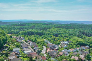 Gökyüzünün altında güpegündüz yemyeşil ağaçlarla çevrili, güzel doğal manzara ve kentsel tasarım entegrasyonunu gözler önüne seren tuhaf bir kasabanın manzaralı hava perspektifi.