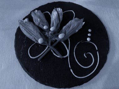 Siyah taş tabağa doldurulmuş kızarmış kabak çiçekleri..