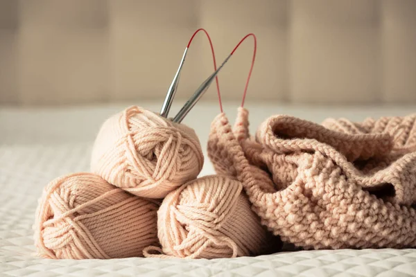Knitting yarn, needles, chunky sweater. Cozy homely atmosphere. Yarn in warm colors of peach, beige. Knitting as a hobby. Accessories for knitting.