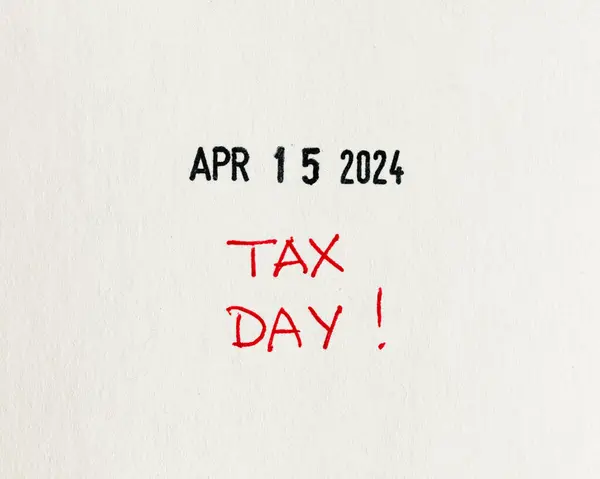 Red \'TAX DAY\' alert handwritten with red pen on textured white paper for April 15, 2024, a reminder to file income taxes, flat lay, top-down view