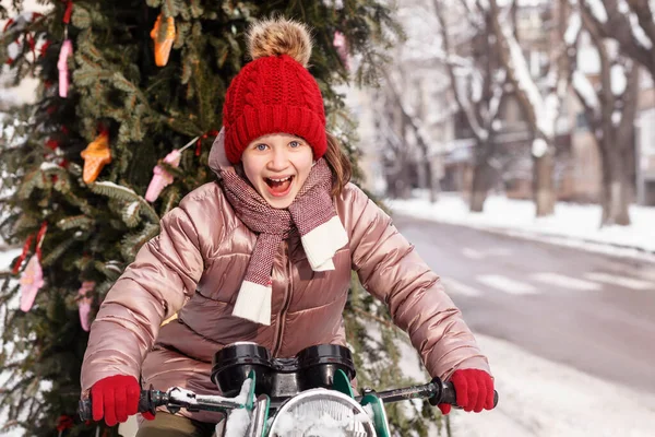 Christmas Tree Delivery Service. Funny Child Girl Have Fun on Winter Snowy Street. Christmas Kid near Cristmas tree.