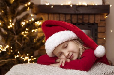 Noel Baba Şapkalı küçük kız Noel Baba 'yı bekliyor. Şömine ve Ağaç' ın yanında Noel Baba 'yı bekliyor. Christmad Tatili