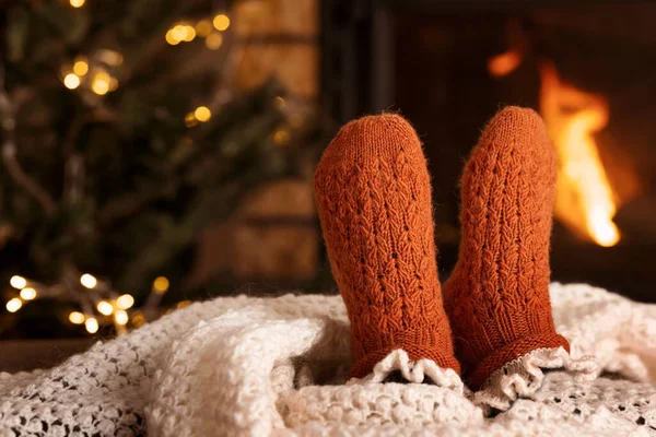 Feet in Wool Socks near Fireplace in Winter time. Resting near fireplace indoors, closeup. Winter vacation