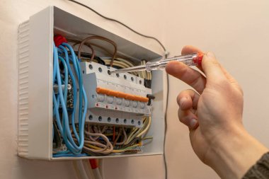 Electrical Switchboard with Automats and Wires. Electrician testing the Electrical Shield Panel. Electric Relay with terminal and cable wiring inside Home.