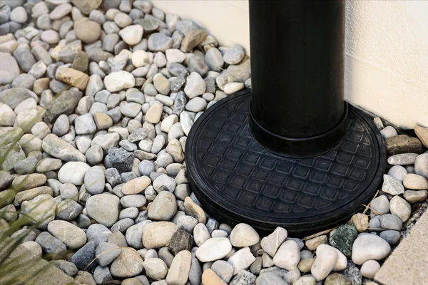 Downspout, Drainage stone Pebble around House, Outdoor close up. French Drain. Sewage pipe, Downpipe, Waterspout rainwater.