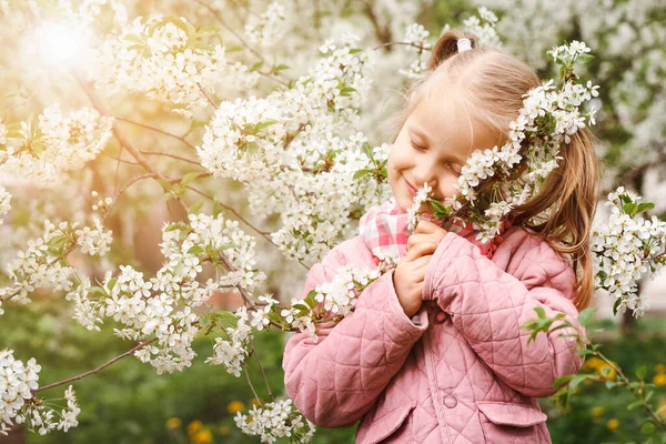 Spring Blossom Flowers for Cute Child in Blooming Garden. Cute Little Girl Kid enjoying Spring Flora