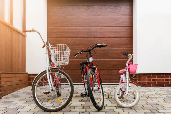 家庭自行车骑的概念 儿童自行车和成人自行车在家庭车库门下 家庭共骑单车 — 图库照片