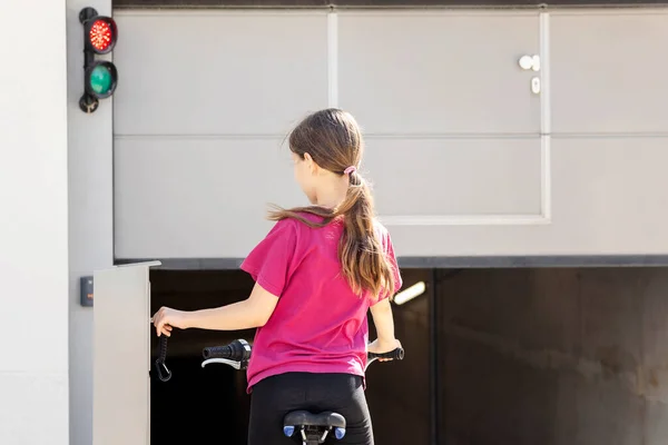 住宅建筑中的车辆存储空间 运输室 自行车 骑自行车的女孩为自行车泊车打开自动车库门 摩托在现代屋的位置 — 图库照片