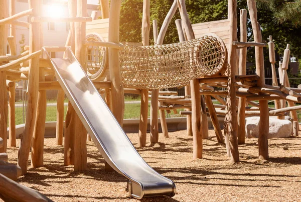 stock image Children Playground  on Public Yard in Park with Swings, Slides and Climbing Equipment. Modern Wooden Playground Equipment of Entertainment Park for Kids.